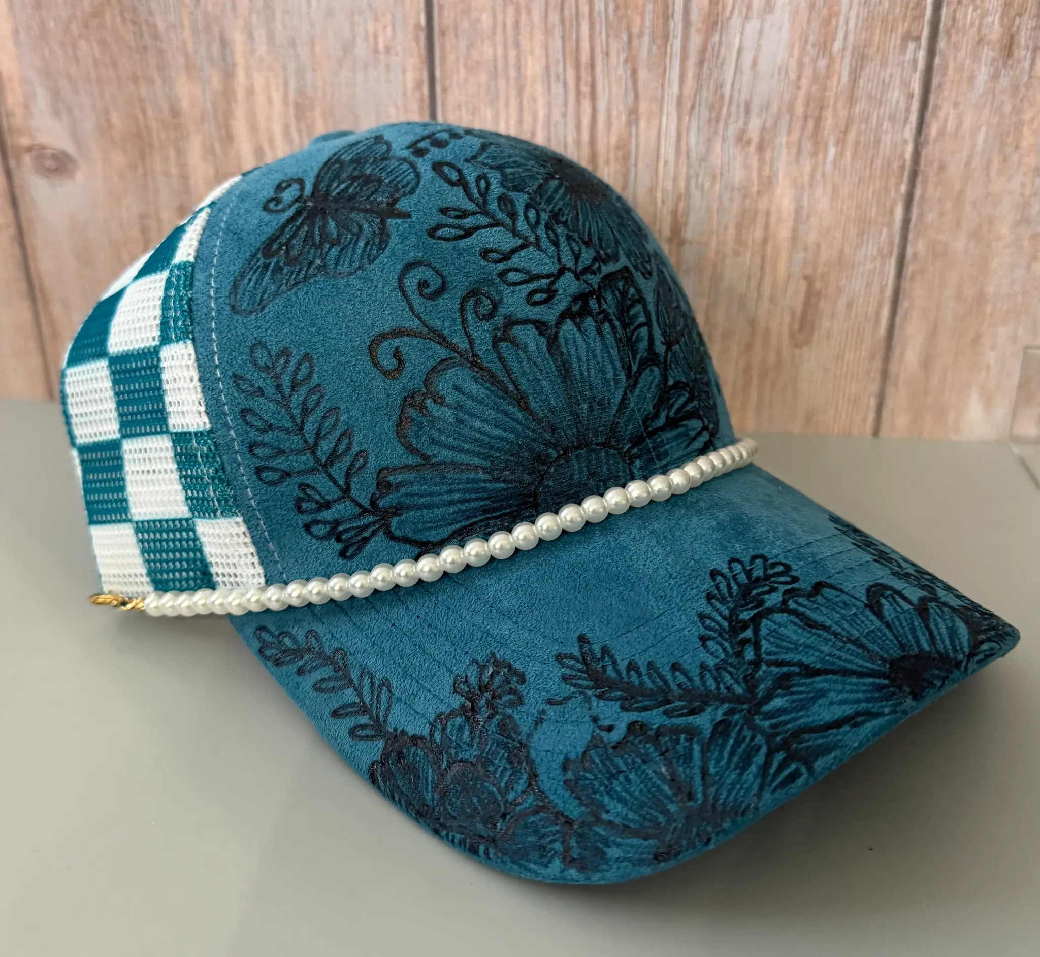 Teal suede cap with hand-burned floral design and pearl trim